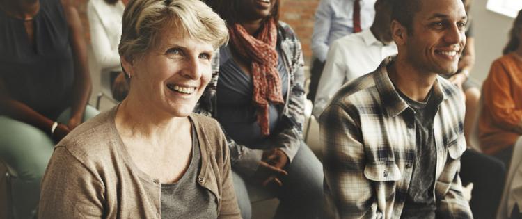 Photo of a group in a meeting, listening intently and smiling