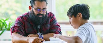 Native man and teen boy sit together at a table